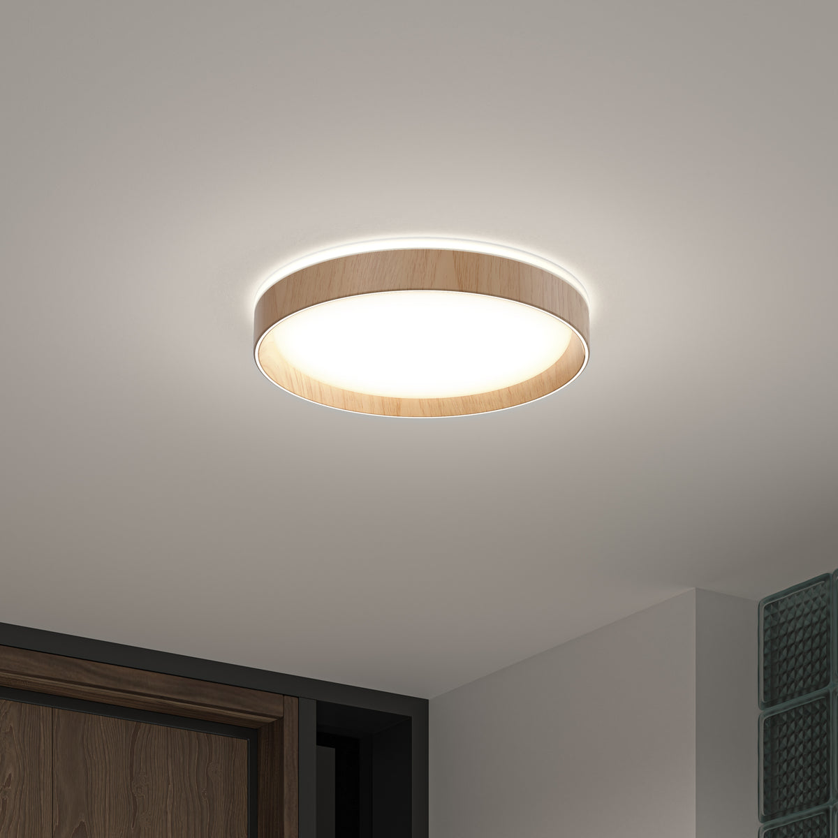 The Artika Callisto 15 in. LED flush mount light, featuring a circular design with a wooden rim and customizable white glow, is installed on a white ceiling above a doorway and glass block wall in a modern interior.