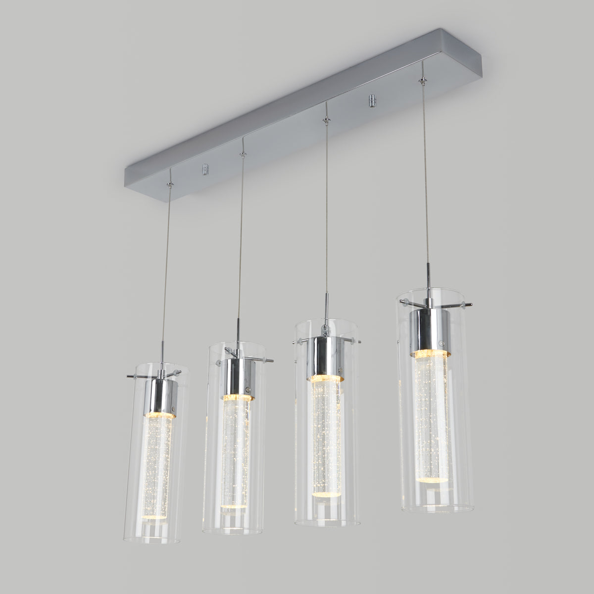 The Artika Essence 4-light LED pendant features four cylindrical glass lights hanging evenly from a sleek rectangular base, emitting a warm white glow.
