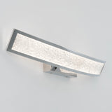 Modern wall-mounted LED light fixture with a rectangular, curved chrome frame and a textured, frosted glass or acrylic panel, emitting a bright, even glow, installed on a plain white wall.