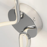 Close-up of a modern, chrome-finished ceiling light fixture with curved LED arms attached to a round metallic base, mounted on a white ceiling.