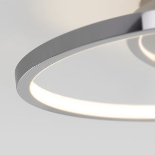 A close-up of the Artika Salto LED flush mount light features its modern circular design and sleek metallic frame, softly glowing against a plain, light-colored background.