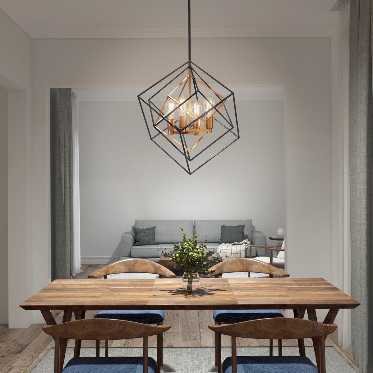 A modern dining room with a wooden table and six chairs, a geometric pendant light above, and a small plant centerpiece. In the background, there is a gray sofa with throw pillows and a blanket in a cozy living area.