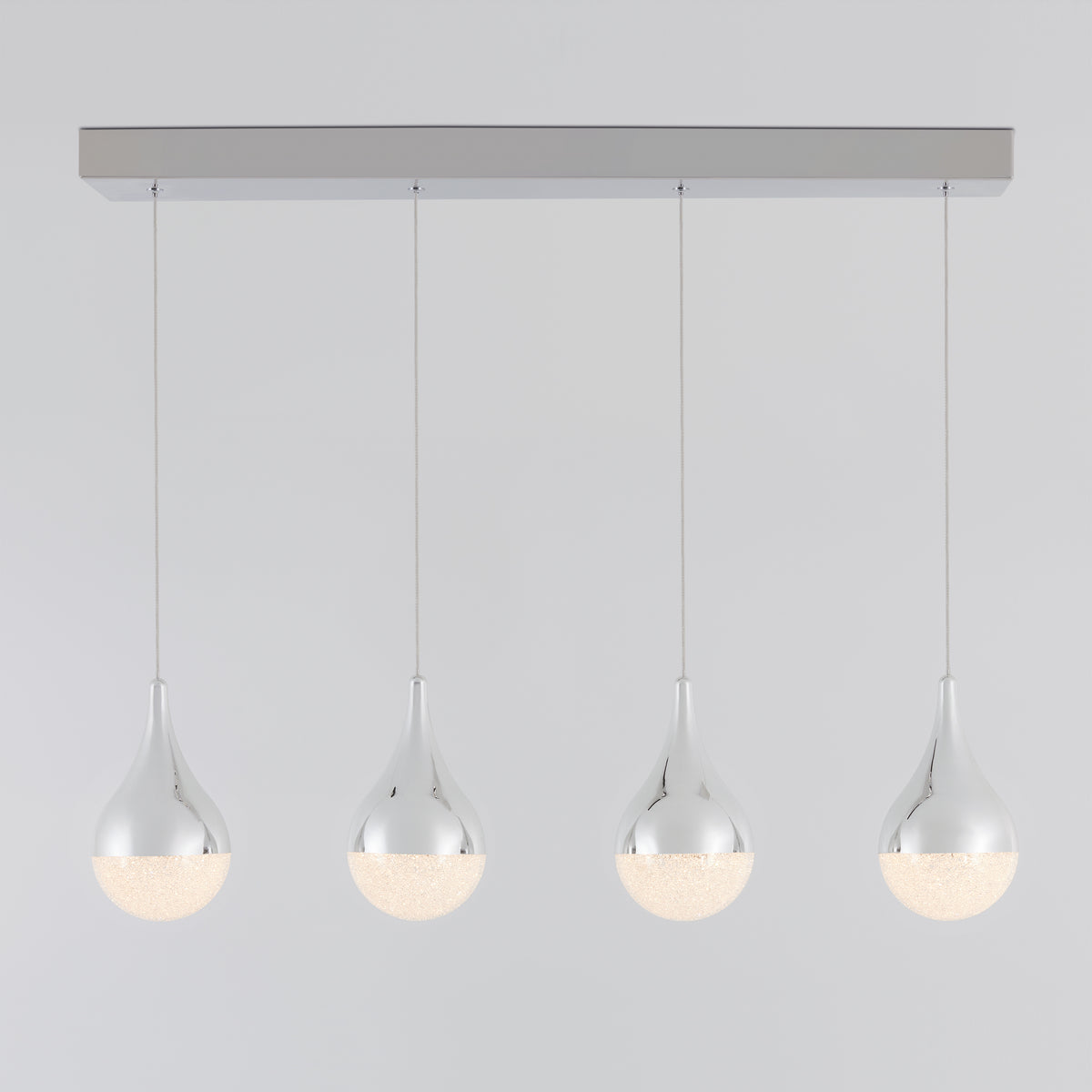 A modern pendant light fixture with four teardrop-shaped, chrome-finished lamps hanging in a row from a rectangular ceiling mount. The lower halves of the lamps emit a soft, diffused light.