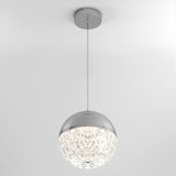 A modern pendant light hangs from the ceiling, featuring a spherical design with a metallic top and a faceted, crystal-like lower half that diffuses light.