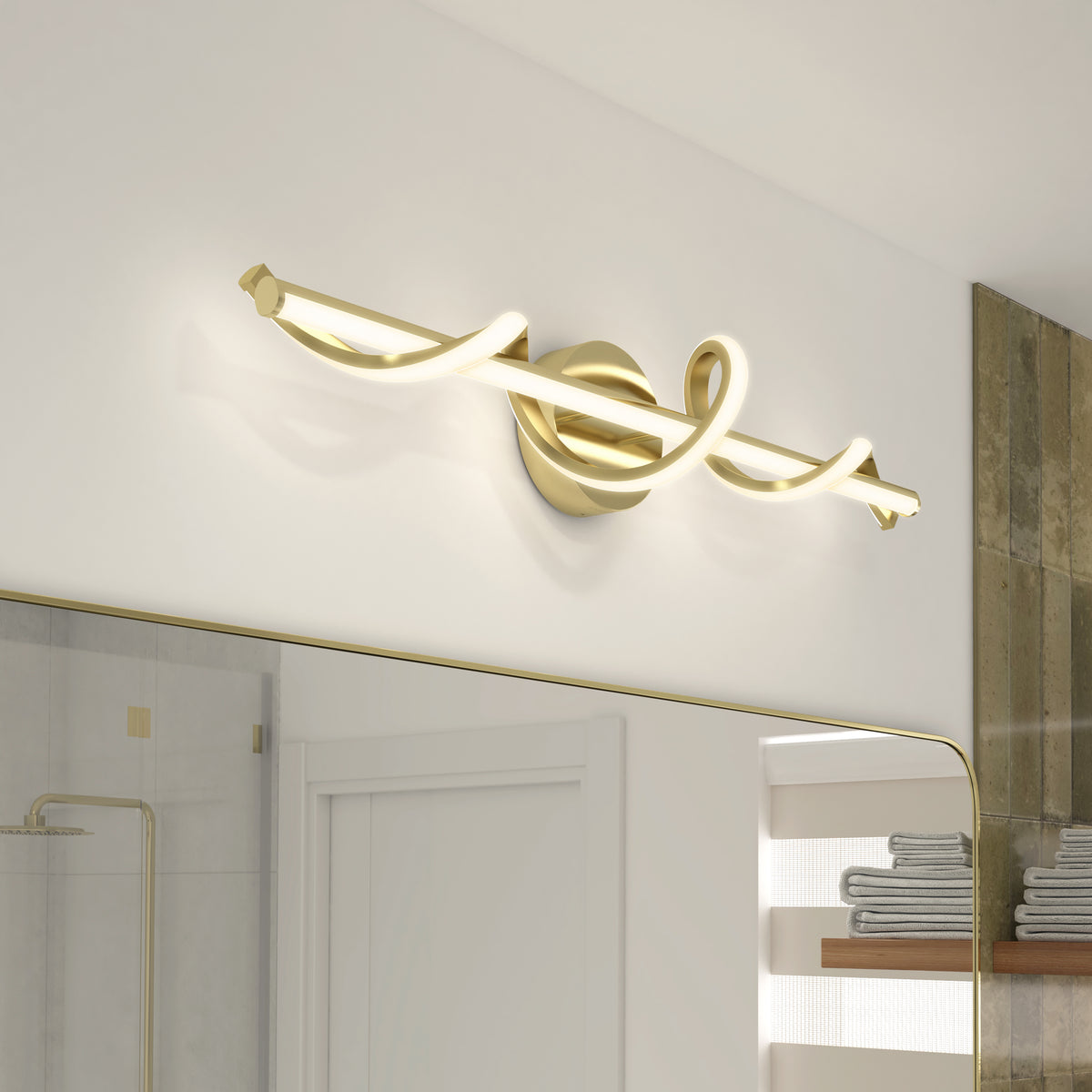 Modern bathroom vanity light with a gold, twisted LED bar design mounted above a large mirror. The fixture emits soft, white light, and towels are visible on shelves in the background.