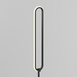 A modern, minimalist floor lamp with an elongated oval shape and a thin, black frame. The inner edge of the oval emits a soft, even light against a plain gray background.