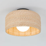 A ceiling light fixture with a woven rattan shade, featuring a round, exposed bulb inside. The natural-colored material creates a warm, textured look against a plain white ceiling.