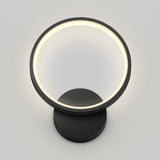 A modern circular wall lamp with a black base and a glowing white ring, mounted on a plain light gray wall.