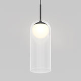 A modern pendant light with a black cord, a glowing white bulb, and a clear cylindrical glass shade, set against a plain light gray background.