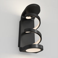 The Artika Swirl indoor-outdoor LED wall light features two spiral, glowing strips on a modern black rectangular base, casting a soft white glow on your wall.
