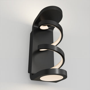 The Artika Swirl indoor-outdoor LED wall light features two spiral, glowing strips on a modern black rectangular base, casting a soft white glow on your wall.