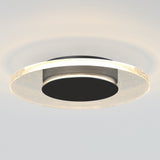 A modern, circular ceiling light fixture with a black center and a translucent outer ring that emits a soft, even glow, mounted on a white ceiling.