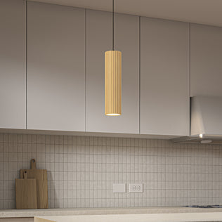 A modern kitchen features light gray cabinets, a beige tiled backsplash with two outlets, cutting boards on the counter, and Artika’s Groove LED modern pendant light (3 CCT) with a textured wood finish above the island.