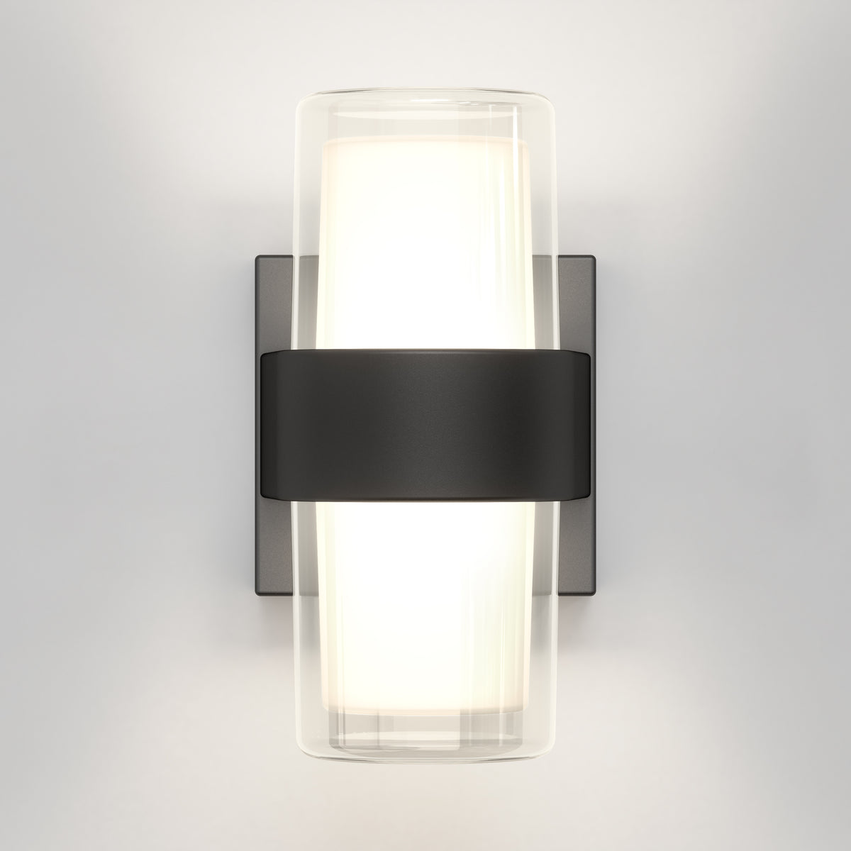 A modern wall sconce with a frosted cylindrical glass shade, mounted on a rectangular metal backplate, featuring a black horizontal band securing the glass. The light glows softly against a white wall.