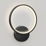 A modern wall-mounted light fixture featuring a circular LED ring with a soft glow and a round black base, set against a plain light gray background.