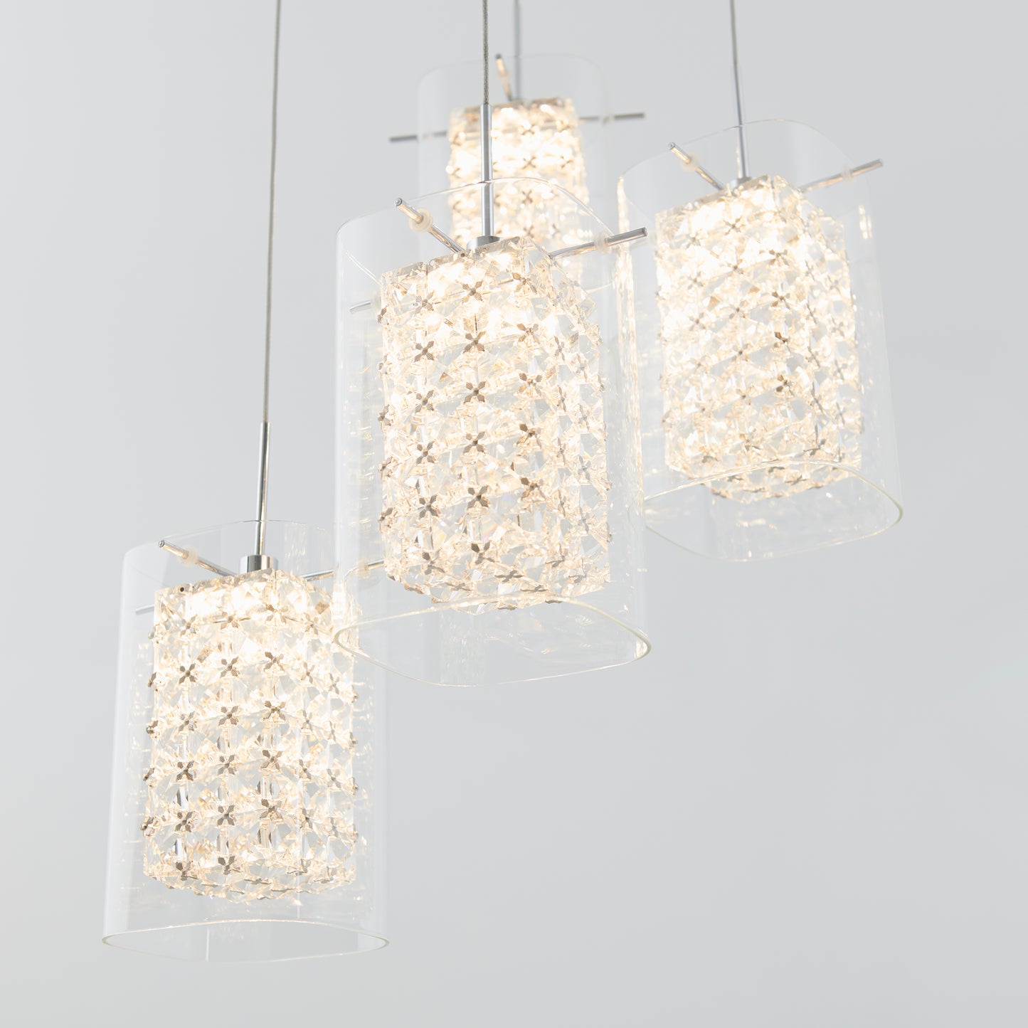 The Crystal Cube 4-light LED pendant light by Artika features modern cylindrical glass shades with sparkling crystal-like accents, suspended at varying heights against a light gray background.