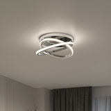A modern ceiling light fixture with intertwined, circular LED bands emits a soft glow in a minimalist room with gray walls, dark curtains, and a window in the background.
