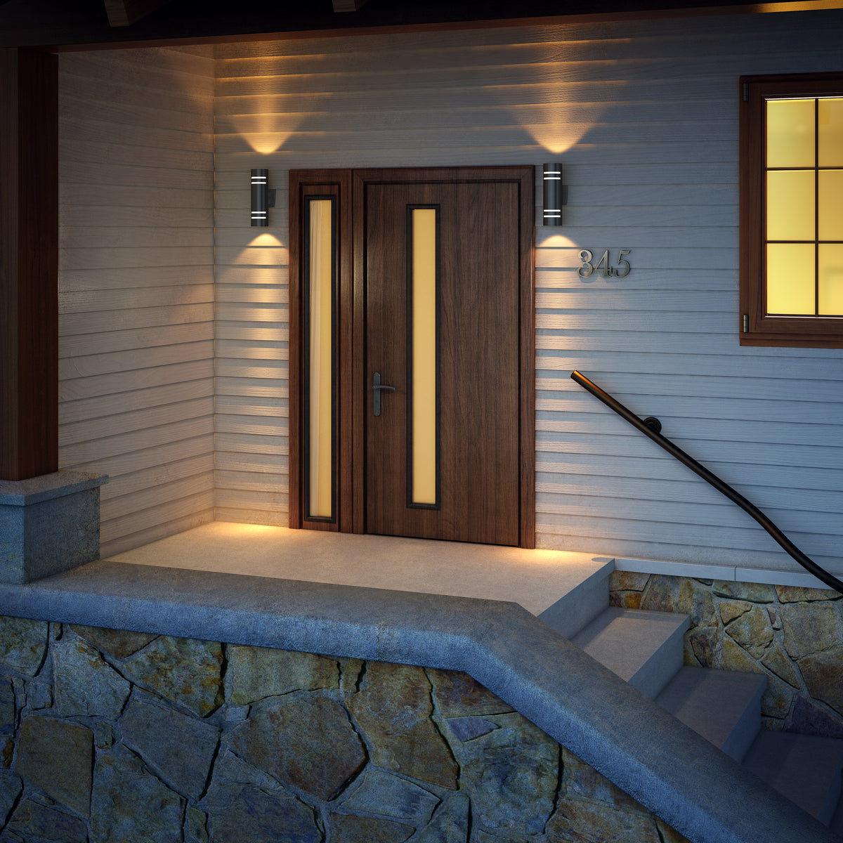 A modern wooden front door with vertical frosted glass panels is illuminated by two wall lights. Stone steps and a stone wall lead up to the entrance, and a metal house number 345 is mounted nearby.