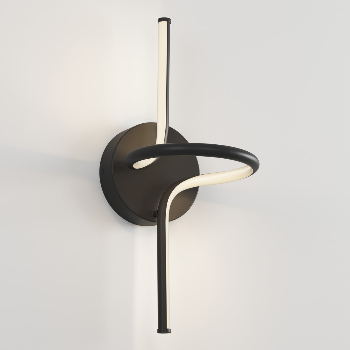 The Artika Swirl LED Sconce features a circular black base and a single curved LED light tube in an abstract design, beautifully mounted on a plain white wall.