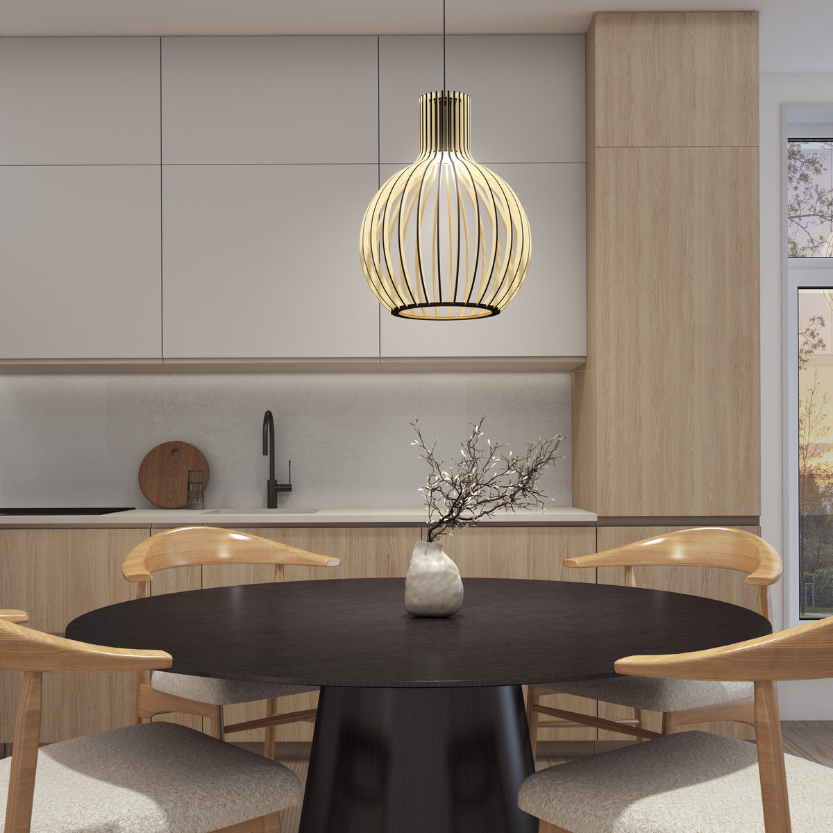 A modern kitchen with light wood cabinets, a round black table with four wooden chairs, a decorative branch in a vase, and the Artika Tomi LED Pendant Light 3 CCT hanging stylishly above the table.