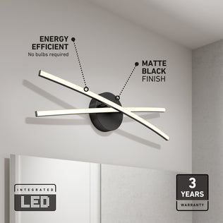 The Artika Orly modern LED bathroom vanity light (3 CCT) features two intersecting bars and a round matte black base, ideal for bathroom mirrors. Labels highlight energy efficiency and matte finish; icons show "Integrated LED" and "3-year warranty".