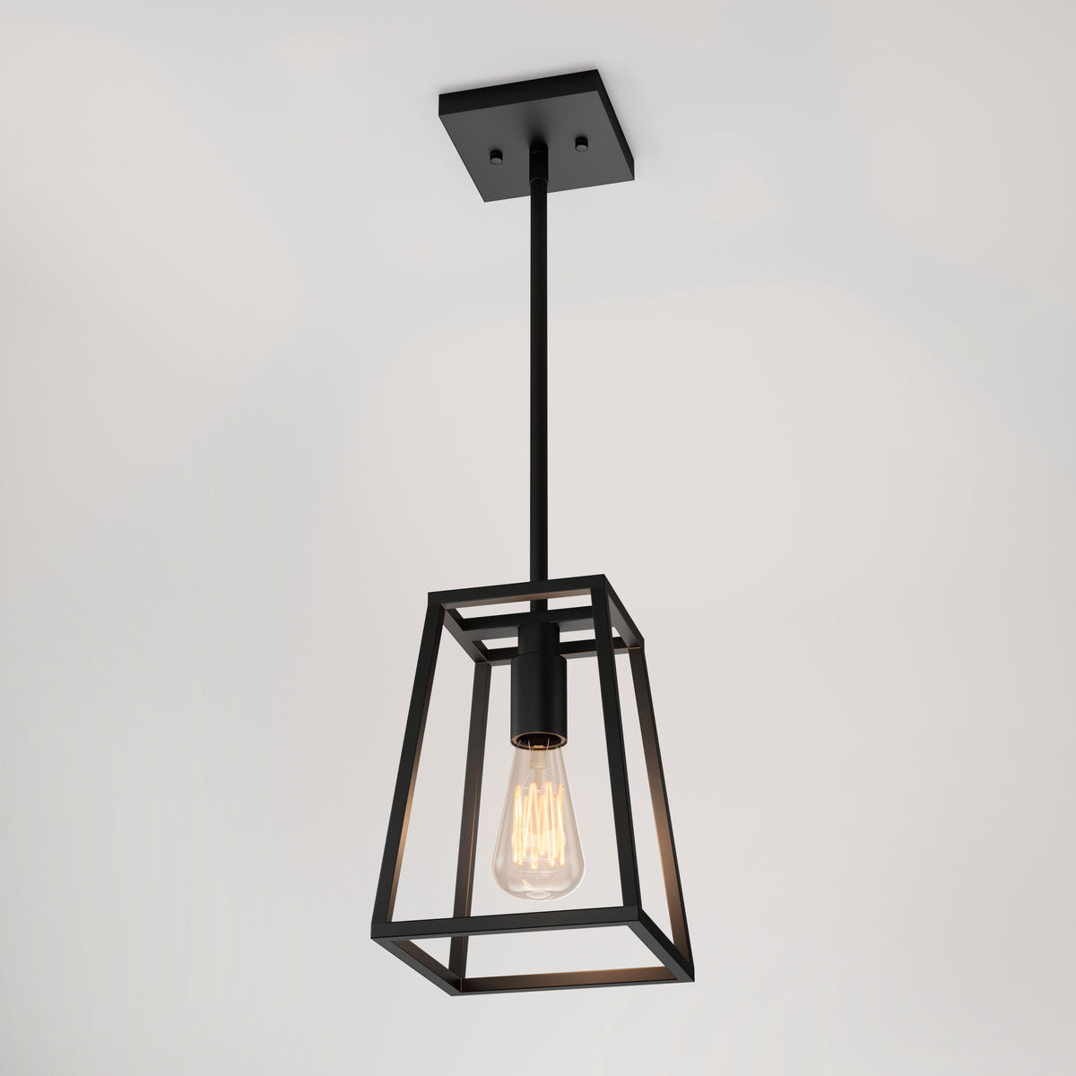 The Artika Carter 1-light pendant is a modern black metal fixture with a geometric open frame, an exposed Edison-style bulb, and hangs from a black rod and ceiling plate against a white background.