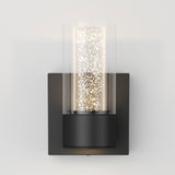 A modern wall sconce with a black square base and a cylindrical glass cover. Inside, small glowing lights create a sparkling effect, giving the fixture a contemporary and elegant appearance.