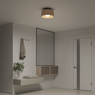 A modern, minimalist entryway features a floating bench with cushion, wall hooks holding a coat, a large mirror, potted plant, and door. The neutral decor is brightened by the Artika Emiko modern LED flush mount light 5 CCT on the ceiling.