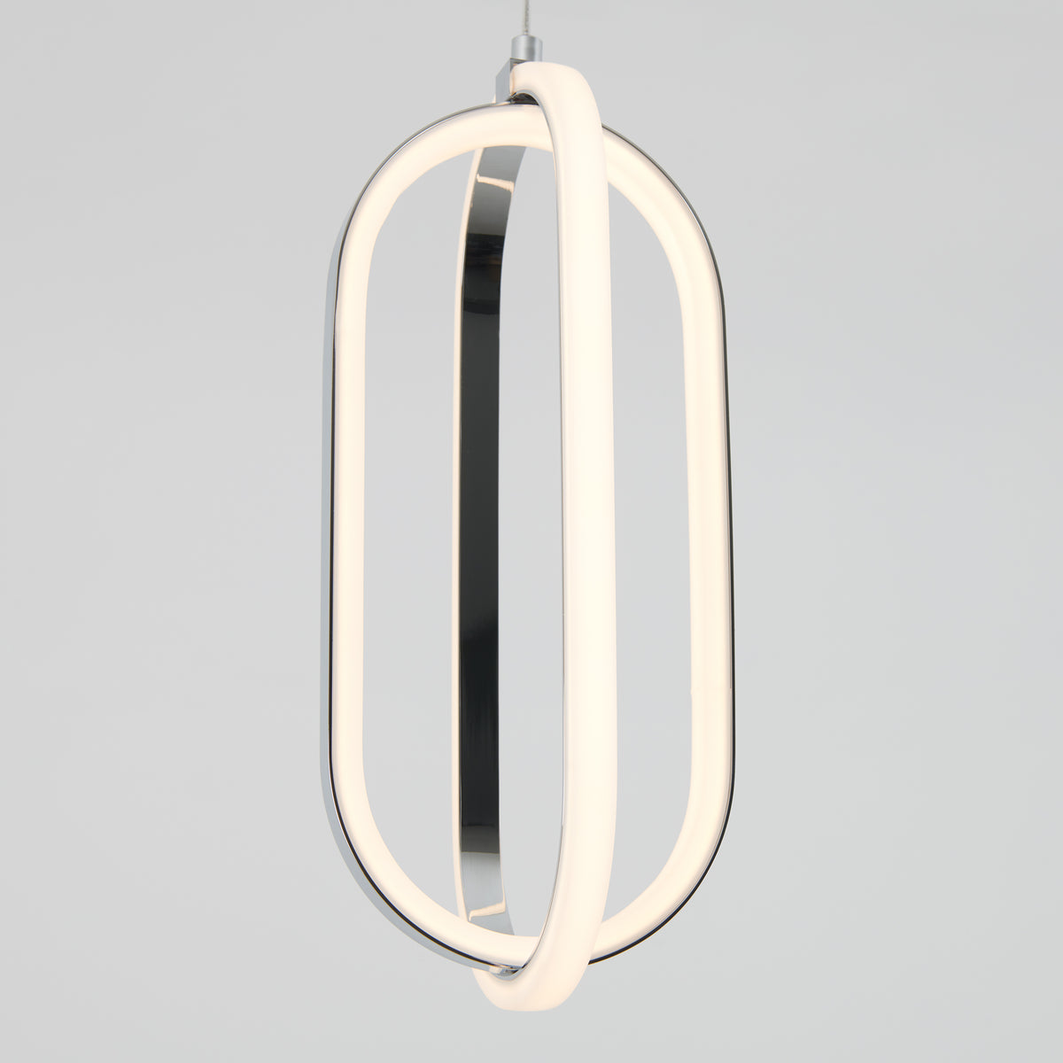 A modern pendant light with two intersecting oval LED loops, emitting a soft white glow, suspended against a plain light gray background.