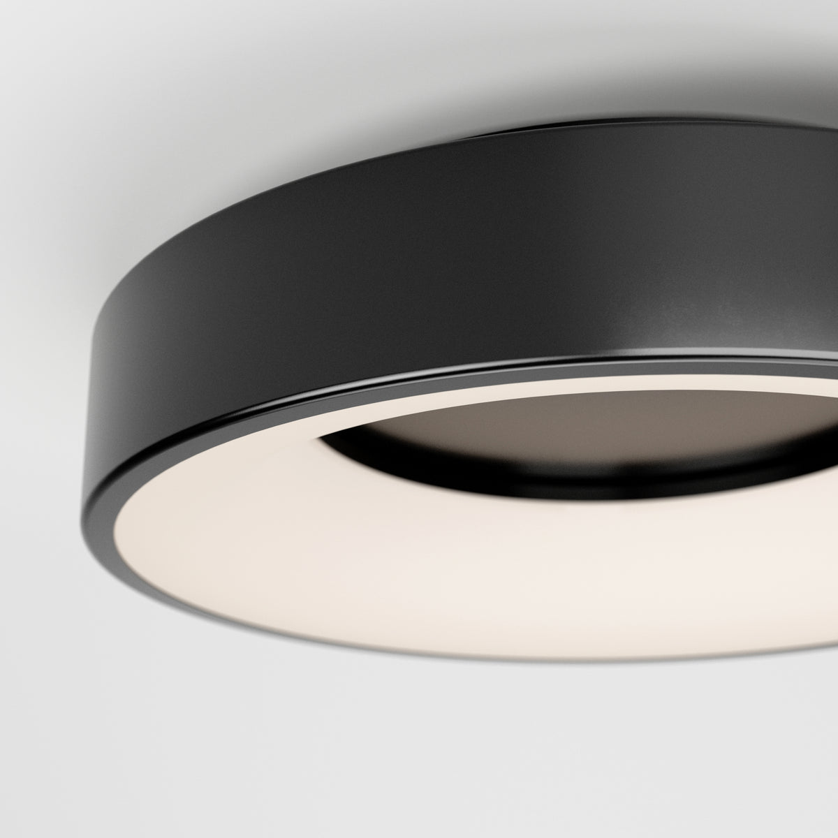 A close-up of the Artika Aiden LED flush mount, a modern circular black ceiling light with a white diffuser, installed on a white ceiling.