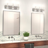 Modern bathroom with two rectangular mirrors above a wooden counter, each with an under-mount sink. A potted plant sits between the sinks, and wall-mounted lights are above each mirror. Chevron tile backsplash is visible.