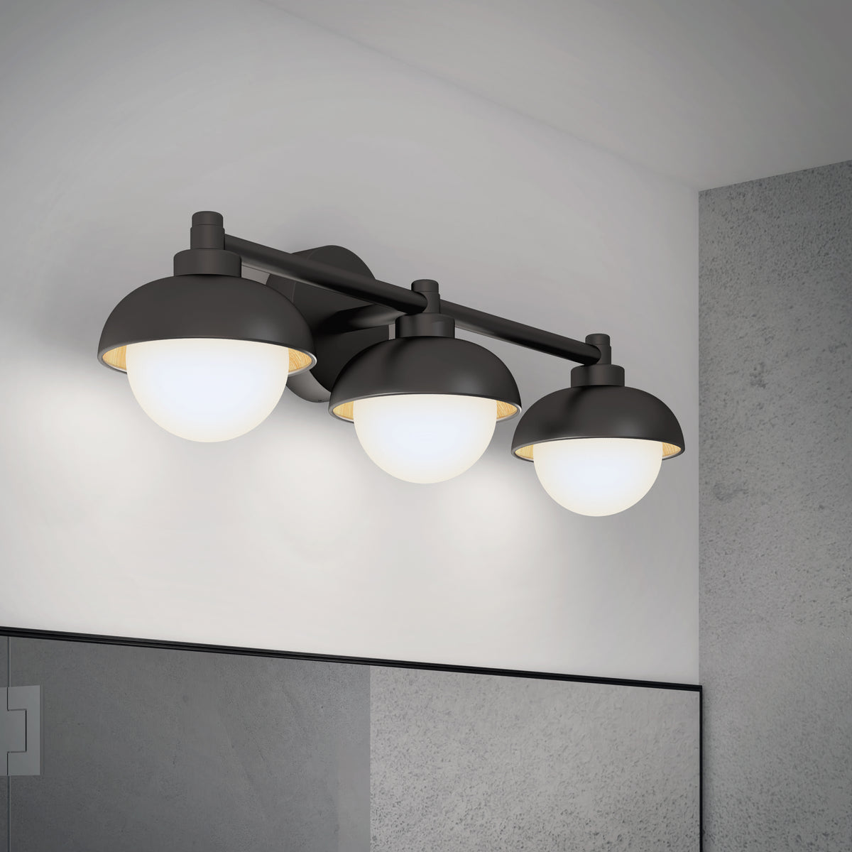 A modern three-light vanity fixture with matte black metal shades and frosted glass globes, mounted above a bathroom mirror on a light gray wall.