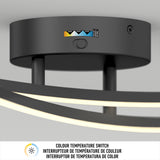 Close-up of a modern black ceiling light fixture with a color temperature switch showing options from warm to cool. Below is a label in English and French, reading COLOUR TEMPERATURE SWITCH.