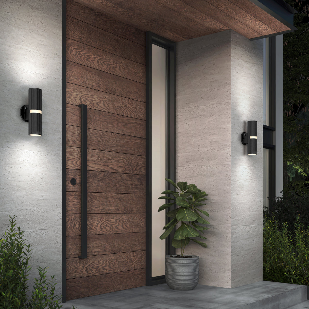 Modern front entrance with a horizontal wooden door, vertical glass panel, tall black handle, and two Artika Groove LED indoor-outdoor wall lights. A large potted plant sits on the concrete porch surrounded by greenery.