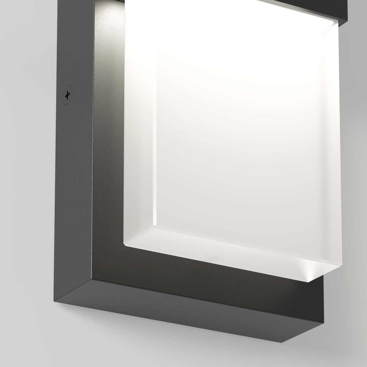 A close-up view of a modern wall-mounted light fixture with a square, frosted glass panel and a dark, rectangular frame, emitting a bright white light.