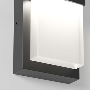 A close-up of the Artika Mazza Frosted indoor-outdoor LED wall light, featuring a black metal frame and a softly glowing frosted white rectangular cover.