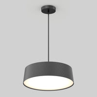 The Artika Groove Drum LED contemporary pendant light features a black, vertically ridged cylindrical shade and hangs from a slim rod, providing a bright, even glow against a plain light gray background.