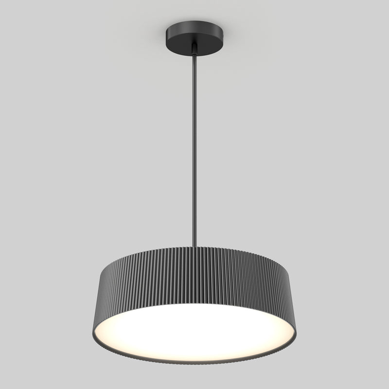 The Artika Groove Drum LED contemporary pendant light features a black, vertically ridged cylindrical shade and hangs from a slim rod, providing a bright, even glow against a plain light gray background.