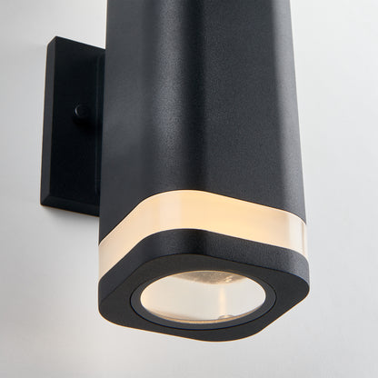 Close-up of the Artika Mettle LED indoor-outdoor wall light, a modern black fixture with a frosted strip near the top that shines upward and downward, shown mounted on a white wall.