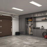 A tidy garage with gray cabinets, shelves, and a brown garage door. Items like tires, storage bins, a toolbox, and a vacuum are organized along the walls; the concrete floor is clean and uncluttered.
