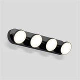 A modern wall-mounted light fixture with four round, evenly spaced LED lights on a sleek black base, set against a plain light gray background.