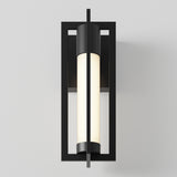 A modern wall sconce with a black rectangular frame and a cylindrical white frosted glass light, mounted vertically against a plain light gray wall.