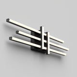 A modern wall-mounted light fixture with four parallel, illuminated bars arranged horizontally and supported by a central black rectangular base against a plain light gray wall.