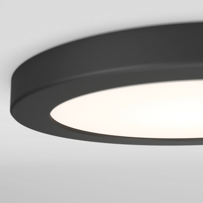 Close-up of the Artika Europa Disk 7 in. LED modern flush mount light, featuring a round black design with a frosted white cover, mounted on a white ceiling and illuminated.