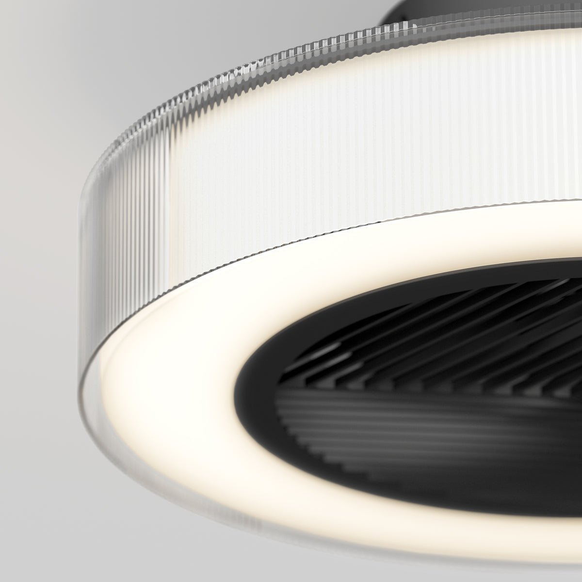 Close-up of a modern circular ceiling light with a ribbed translucent outer rim, a glowing white LED ring, and a black textured center against a light gray background.