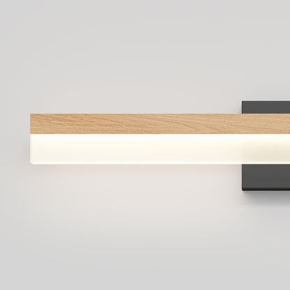The Artika Neil modern LED bathroom vanity light features a rectangular wooden top, white frosted bottom, and black base. Mounted against a light gray background, it emits a soft, even glow for minimalist style.