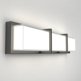 A modern rectangular wall sconce with three frosted glass panels framed in dark metal, mounted on a white wall, emitting a bright, even light.
