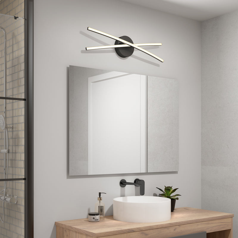 Modern bathroom with a large mirror, wooden countertop, white sink, black faucet, and potted plant. Above the mirror is the Artika Orly 25-in Modern Integrated LED 3-CCT Vanity Light, enhancing the contemporary decor. Shower area partially visible.