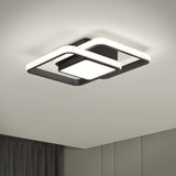 A modern, square ceiling light fixture with intersecting black and white geometric frames, mounted on a white ceiling above a room with gray curtains and light-colored walls.