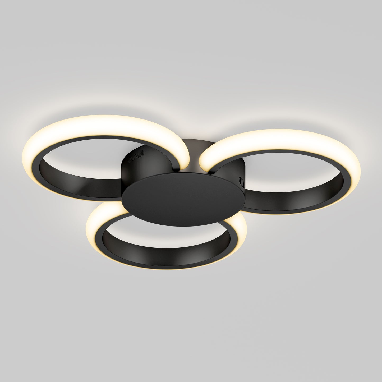 The Artika Nyala 15 in. LED flush mount light 5CCT features three interlocking black rings with glowing white LEDs, all mounted on a round black base and shown against a plain gray background.